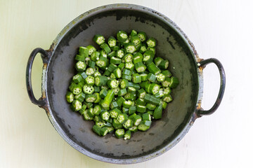 Chopped okra or lady's fingers in a korai. Okra is a fruit, but it's used as a vegetable in cooking. Its scientific name is Abelmoschus esculentus and also known as Bhendi, Dherosh, Bhindi, Vendi.