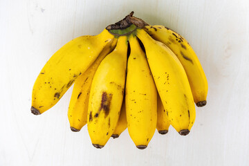 A bunch of fresh ripe yellow bananas on wooden textured white background. Bananas are healthy fruit. - obrazy, fototapety, plakaty