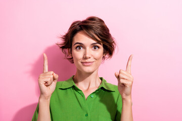 Photo of cheerful positive young woman dressed green shirt pointing two fingers up empty space...