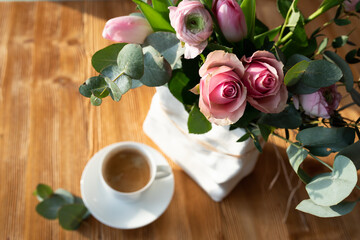 Still life with pink roses and cup of coffee. Background  for mother's day greetings. Top view with short depth of field and space for text.