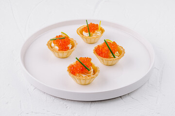 Elegant tartlets with salmon caviar on white plate - obrazy, fototapety, plakaty