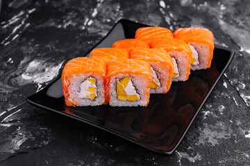Fresh salmon sushi roll on elegant black plate