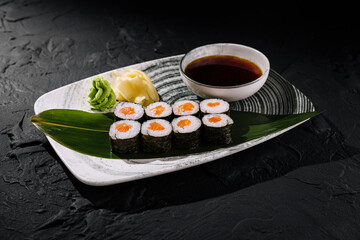 Exquisite sushi platter with soy sauce on dark background