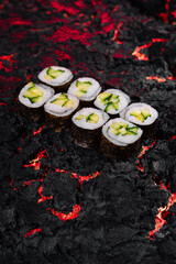 Avocado sushi rolls on fiery lava texture background