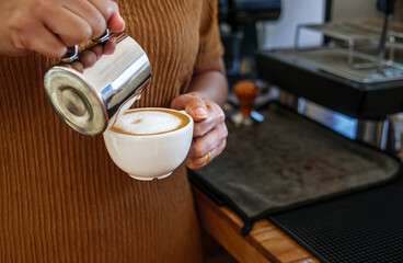 Barista pouring milk into coffee making a cappuccino. Barista making cappuccino,Professional bartender preparing coffee drink