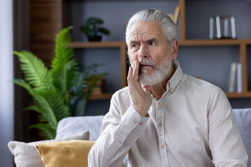Senior man touching his cheek, showing signs of toothache