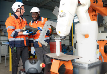 Diverse group of engineer in safety uniform maintenance and examining robot arm machine in modern...