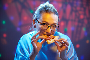 45 year old woman with glasses eats pizza