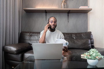 Professional man working remote from home with technology. African American male has a business...