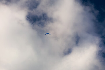Paragliding extreme sport. Photo with a sportsman while practicing paragliding. Blue sky white...