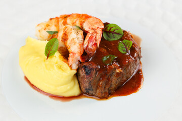 Surf and turf dish. Photo with a surf and turf gourmet plate made from shrimps, beef tenderloin filet mignon steak and mashed potatoes.