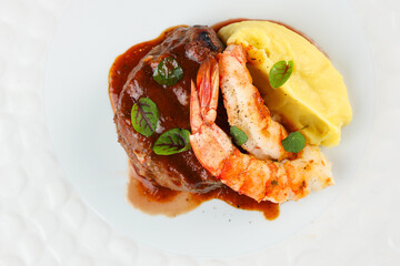 Surf and turf dish. Photo with a surf and turf gourmet plate made from shrimps, beef tenderloin filet mignon steak and mashed potatoes.