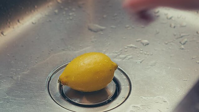 Woman washing fresh lemon, removing germs and pesticide residues from lemon skin with hot water. High quality 4k footage