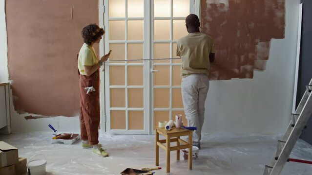 Rear full footage of diverse spouses measuring doorway width with tape during house remodeling process