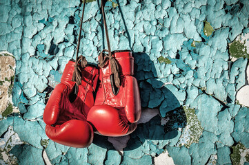 Red professional boxing gloves on the cracked wall