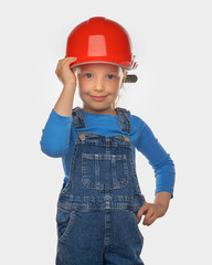 Little girl worker in a safety helmet with a tool on a light background.