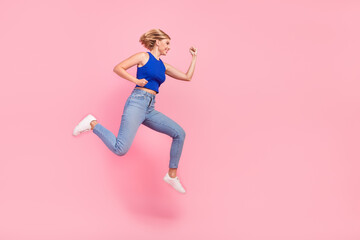 Fototapeta na wymiar Full size photo of pretty young woman run jump empty space wear blue top isolated on pink color background