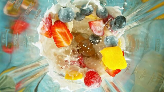 Super slow motion of mixing pieces of berries in blender with milk, camera movement, top shot. Filmed on high speed cinema camera, 1000 fps.