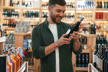 Front view. Man is choosing wine in the store