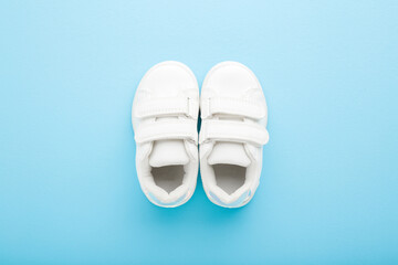 New white leather sport shoes for little kid on light blue table background. Pastel color. Baby footwear. Closeup. Top down view. - 788291002