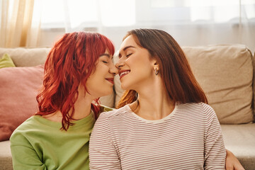peaceful moment of young happy lesbian couple with closed eyes smiling at home, bliss and love