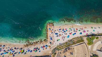 Top view, splendid aerial view of some people relaxing on a beautiful beach washed by the sea....