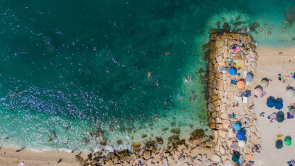 Top view, splendid aerial view of some people relaxing on a beautiful beach washed by the sea....