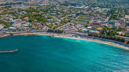 Fototapeta premium Top view, splendid aerial view of some people relaxing on a beautiful beach washed by the sea. Bisceglie (Apulia, Italy)