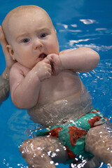 Baby popping his knuckles, nervous in the water. Closeup. Swimming lessons for newborn.