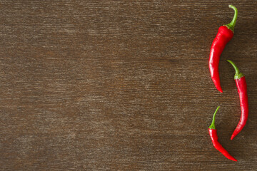 Fresh red hot chili peppers on dark brown wooden table background. Closeup. Empty place for text. Top view. - 788300069