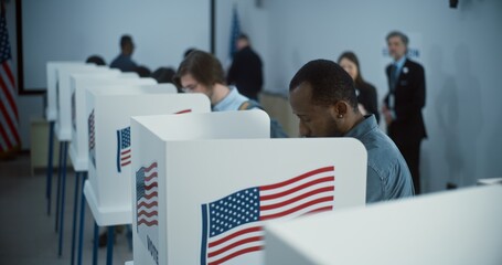 African American citizen comes to vote in booth in polling station office. National Election Day in...