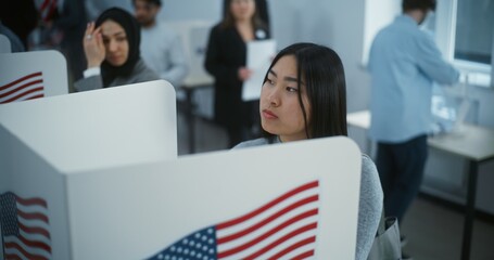 Asian female American citizen votes in booth in polling station office. National Elections Day in...
