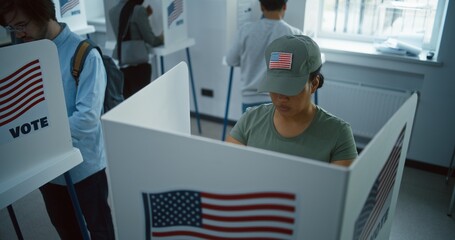 Female American soldier comes to vote in booth in polling station office. National Election Day in the United States. Political races of US presidential candidates. Concept of civic duty. Dolly shot. - obrazy, fototapety, plakaty