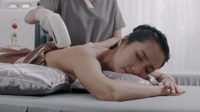 Young Asian female client getting laser treatment procedure in spa salon