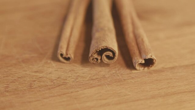 Dried bark cinnamon strips on a wooden rustic table. Handheld. Slow motion. Close up. Interior, kitchen. Studio shot. High quality 4k footage