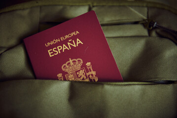A Spanish passport in a green backpack pocket