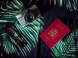 A Spanish passport, a camera and sunglasses over a Hawaiian bedcover - obrazy, fototapety, plakaty