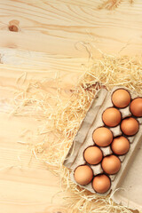 Chicken eggs in a cardboard box, top view. Eggs on a wooden background. Ten fresh raw eggs. Brown chicken eggs in a recycled cardboard tray on a wooden table