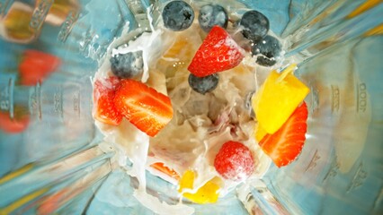 Freeze motion of mixing pieces of berries in blender with milk, top shot