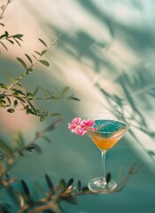Cocktail in a glass with a pink flower on a green background.