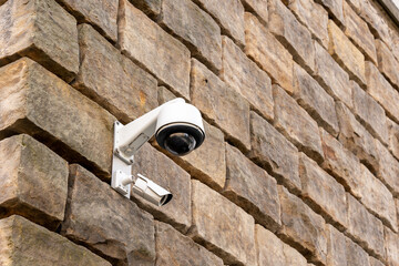 A CCTV camera is installed on a stone wall. Security and protection concept.
