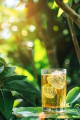 Iced tea glass among green leaves, sunlit bokeh effect