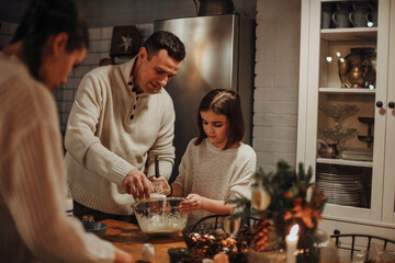 Young family, father mother and daughter cooking homemade cake together in cozy kitchen