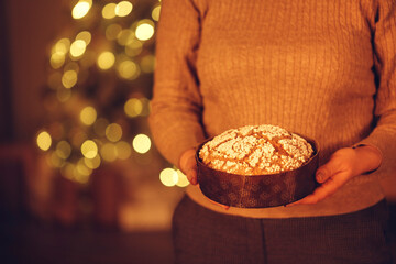 Woman holding delicious freshly baked homemade Christmas pie while standing against xmas tree