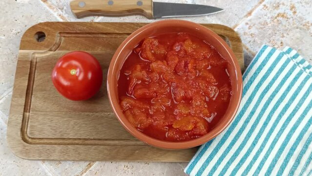 bol de tomates concass&eacute;es, en gros plan, sur une planche &agrave; d&eacute;couper	