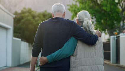 Senior couple, walk and hug in city, road and driveway of house for love, peace and support outdoor. Elderly people, freedom and retirement together in nature, environment or urban with back view