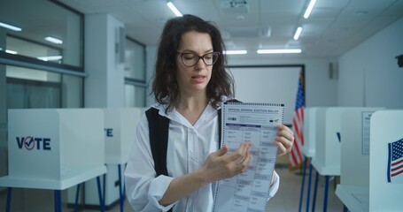 American woman speaks on camera, shows paper bulletin, calls for voting. National Elections Day in...