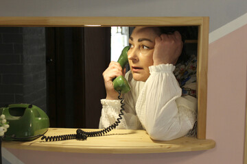A woman is talking on the phone indoors,retro, old-style phone
