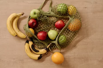  Top view of shopping bag with assortment of fruits including spoiled and fresh bananas, ripe green and red apples and juicy oranges © pressmaster