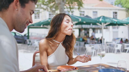 Hungry girl eating lunch at street cafe with husband closeup. Lovers dinning